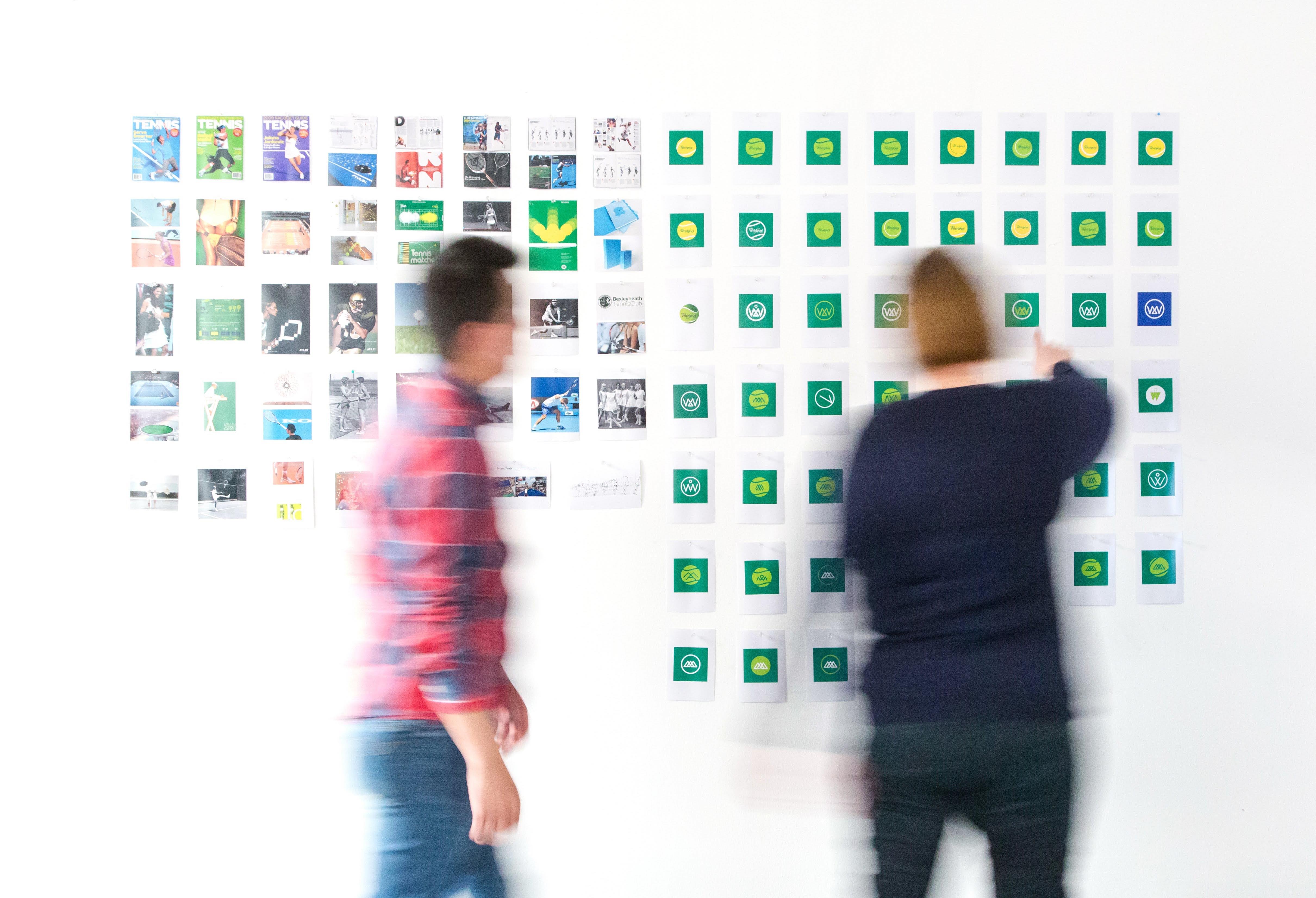 Variety of icons and designs on a wall with two people working on them